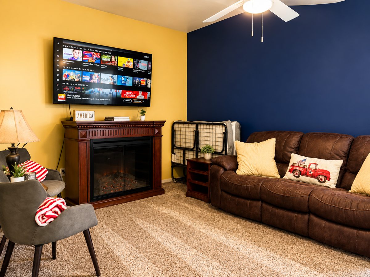 Living room with fireplace, leather sofas, and Smart TV